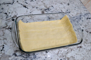 Crescent dough sheet pressed into a greased 9x13 glass baking dish