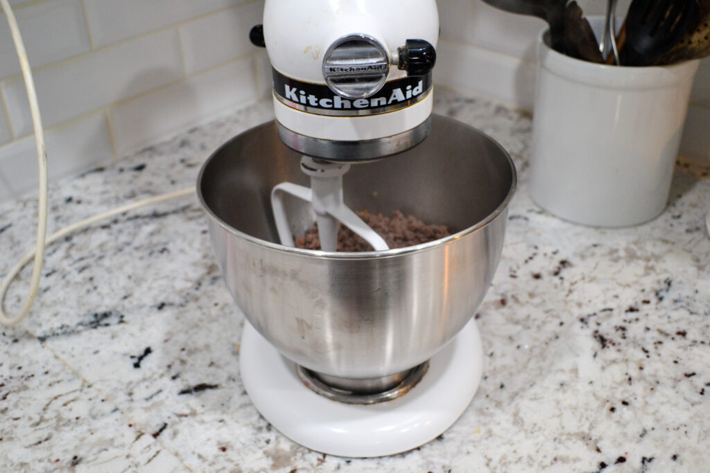 Cooked sausage in a stand mixer bowl with the paddle attachment