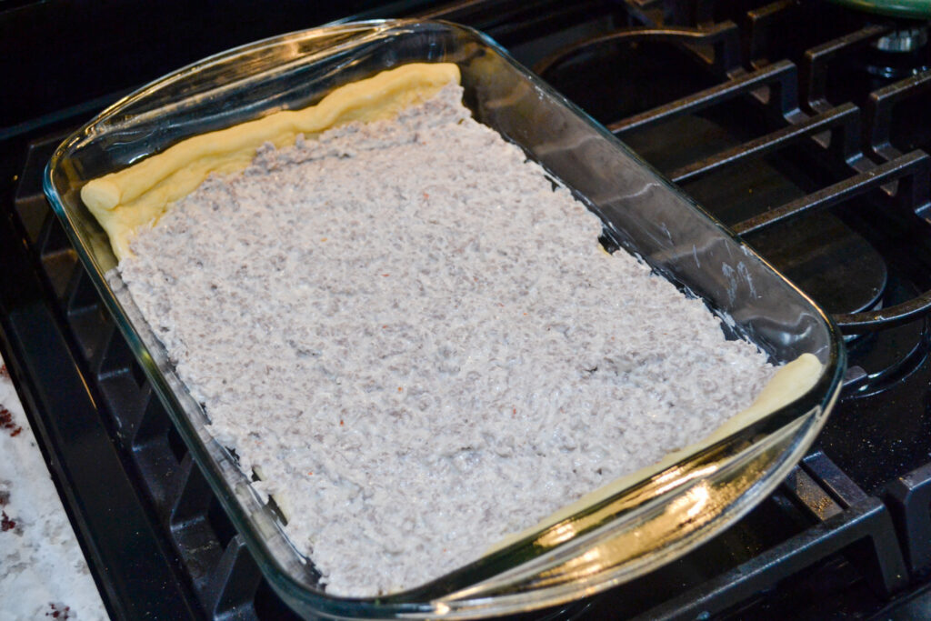 Sausage cream cheese filling spread over the crescent crust