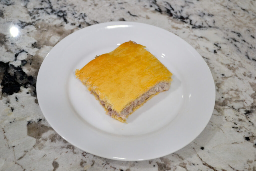 Slice of sausage cream cheese crescent casserole on a white plate