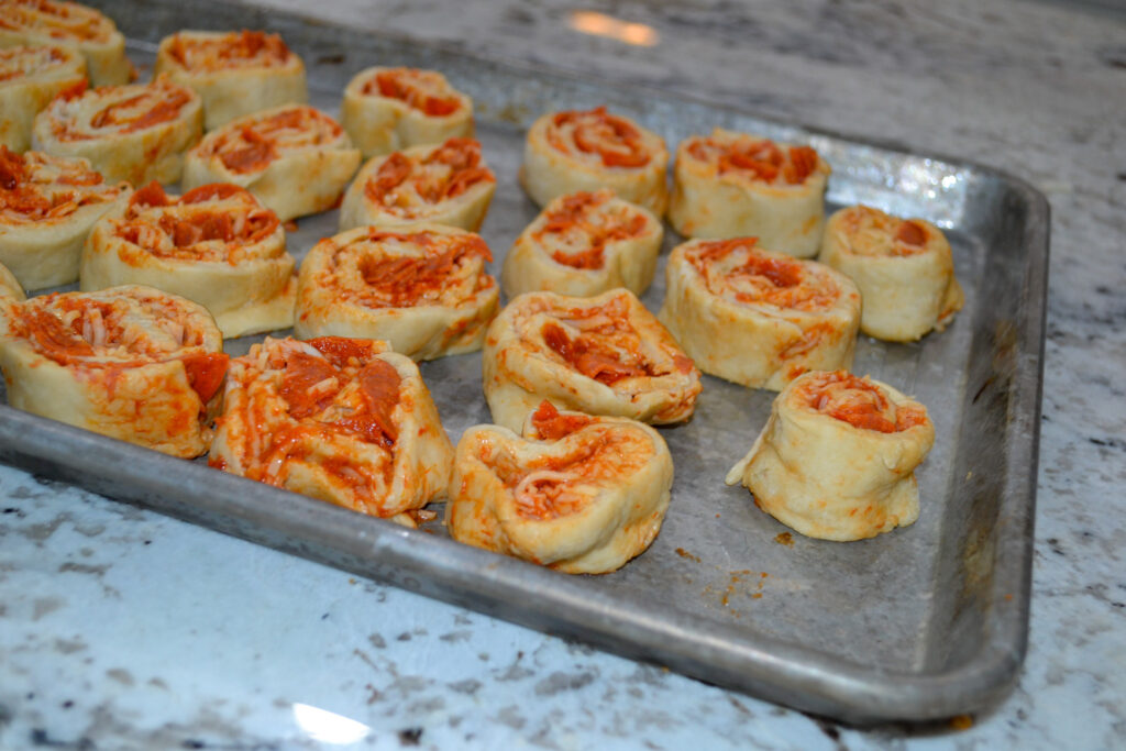 Baked pepperoni pizza pinwheels on a baking sheet