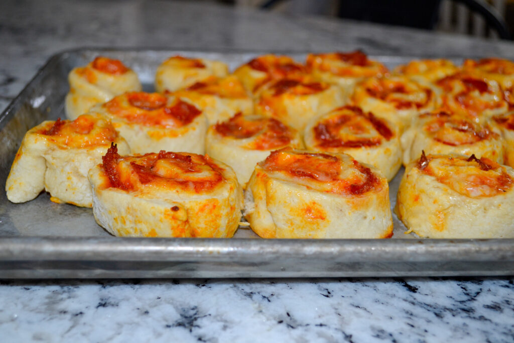 Golden pepperoni pizza pinwheels fresh out of the oven on a sheet pan
