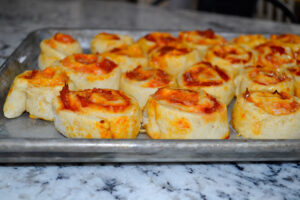 Golden pepperoni pizza pinwheels fresh out of the oven on a sheet pan