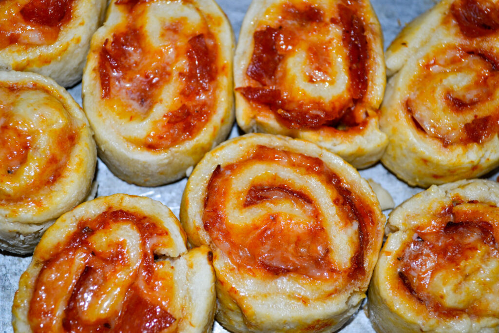 Close-up of baked pepperoni pizza pinwheels showing the cheesy swirl