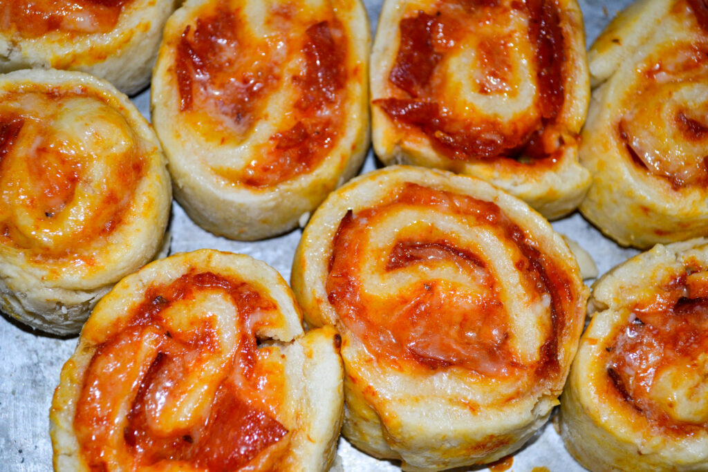 Cheesy pepperoni pizza pinwheels close up on a baking sheet