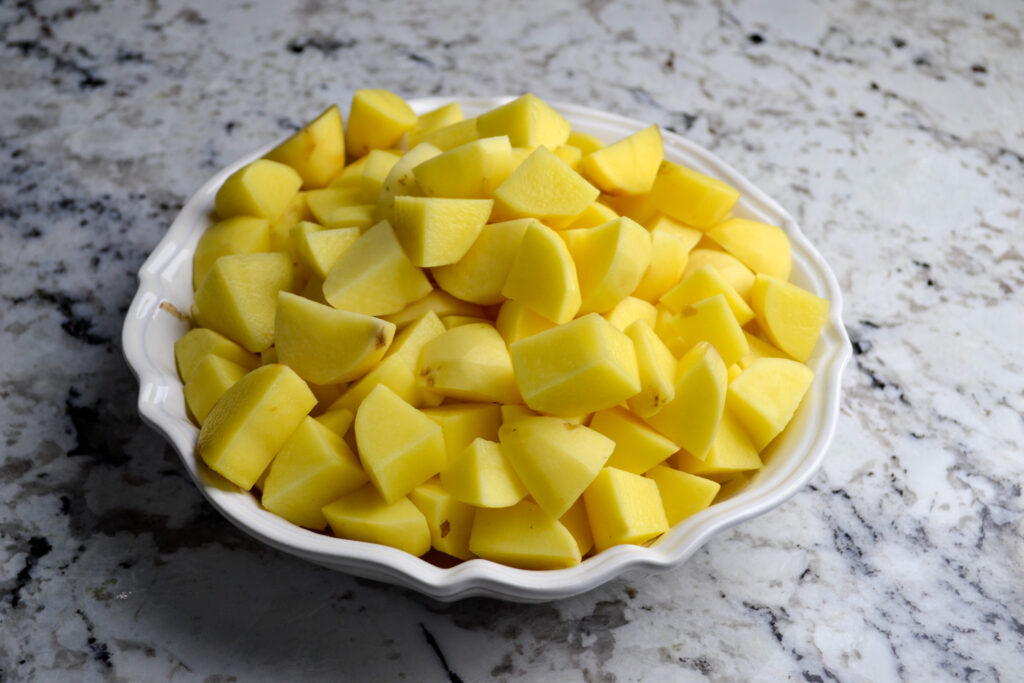 Peeled and diced potatoes in a white bowl, ready for potato soup