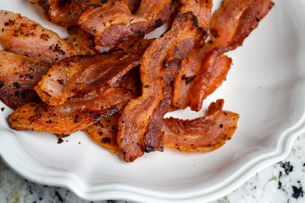 Crispy cooked bacon strips on a white plate