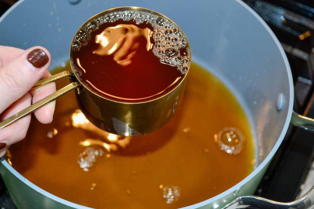 Pouring beef broth into the pot of taco soup