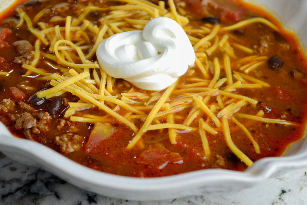 Bowl of taco soup with ranch topped with shredded cheese and sour cream