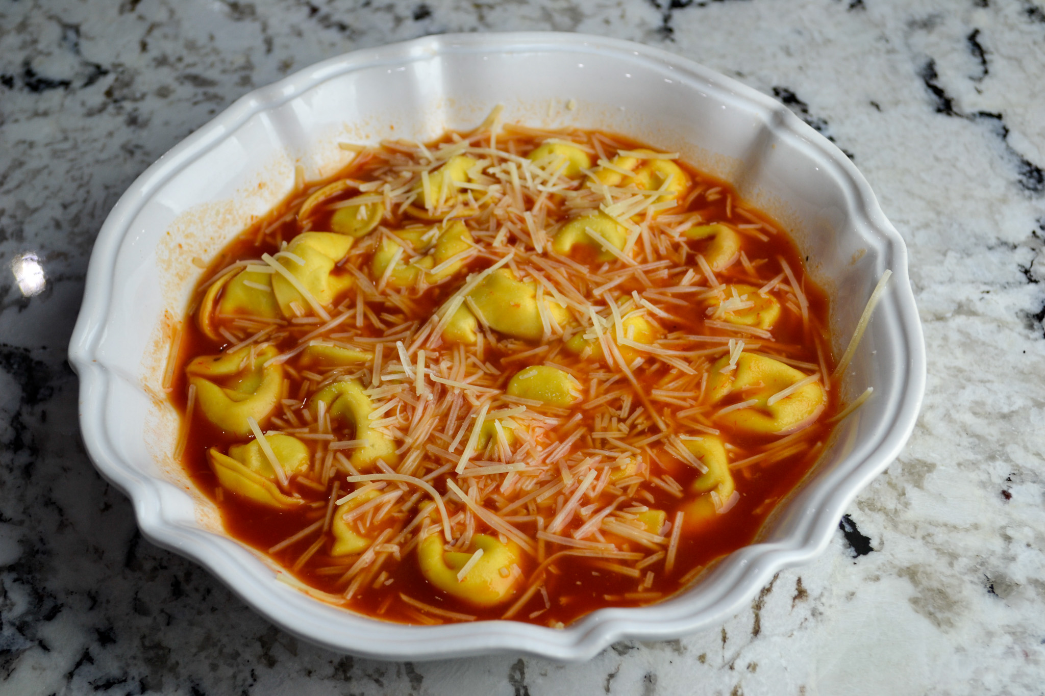 Overhead view of creamy tomato cheese tortellini soup in a white dish