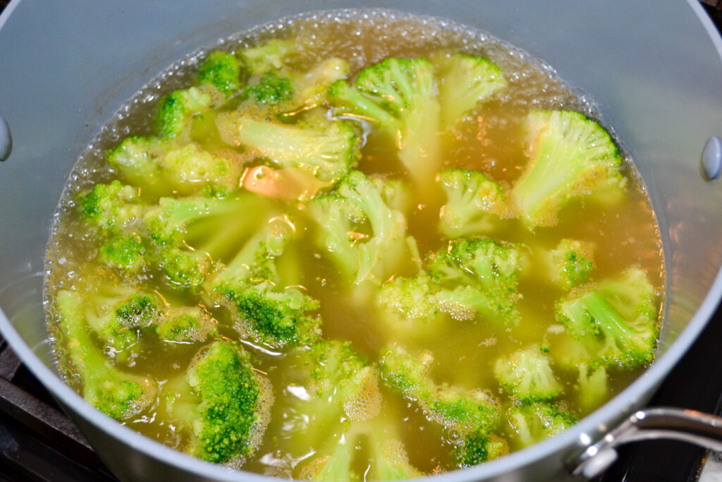 Broccoli florets simmering in chicken broth until tender
