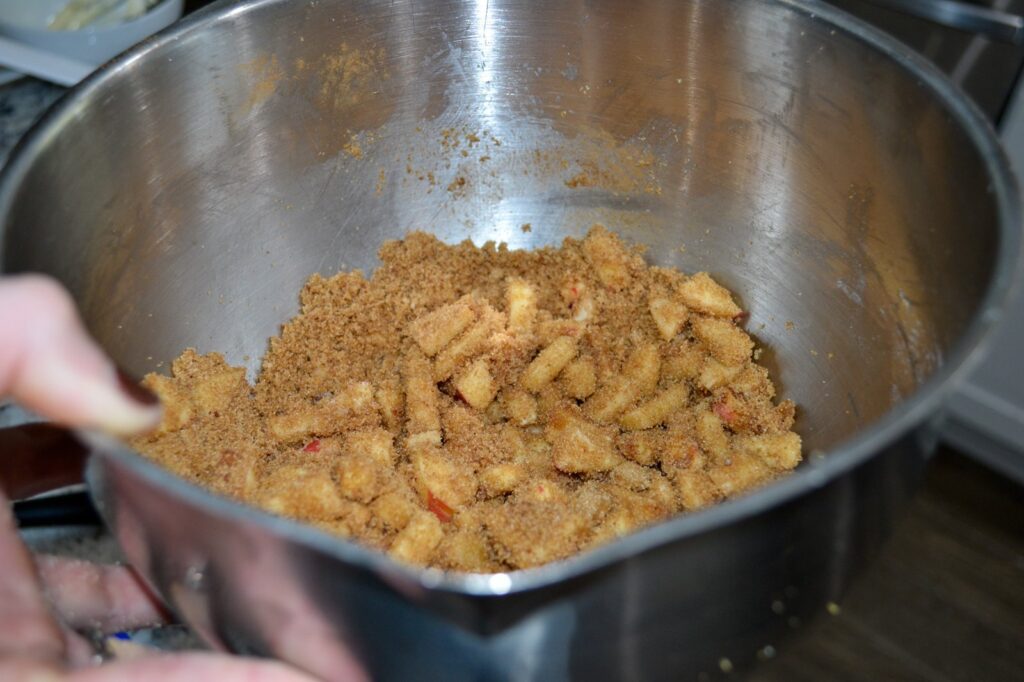 Diced apples tossed with brown sugar, cinnamon and flour in a mixing bowl